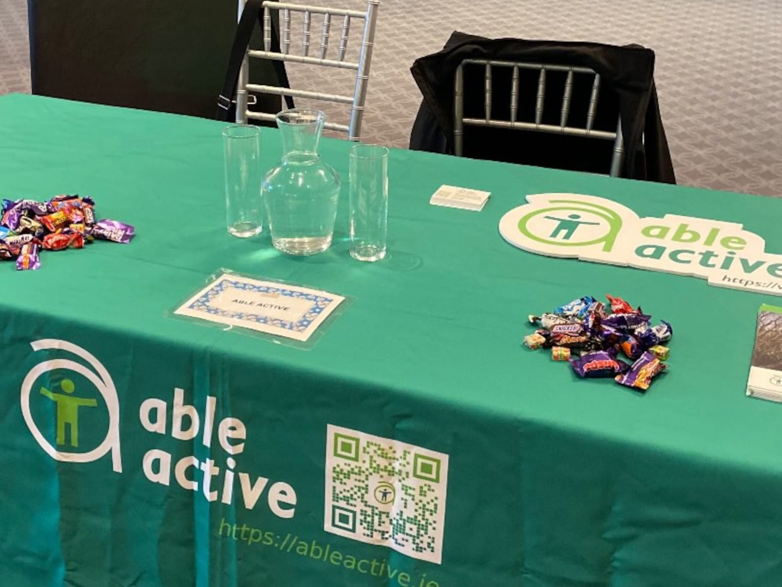 Exhibitor table with branded tablecloth and two piles of chocolates